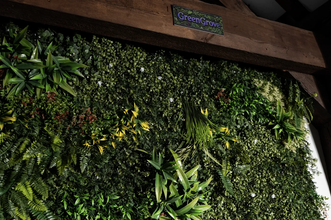 Zielona ściana w lofcie Fresh Loft w Szczecinie - panel z mchu i roślin pod drewnianą belką stropową